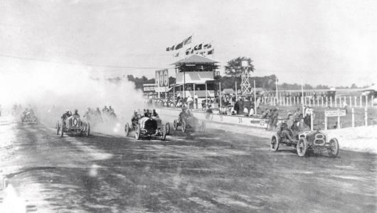 The start of the 300 mile race for the Wheeler-Schebler trophy at the Indianapolis Motor Speedway in 1909, which was the feature race on the last day of a three-day period of automobile racing.
