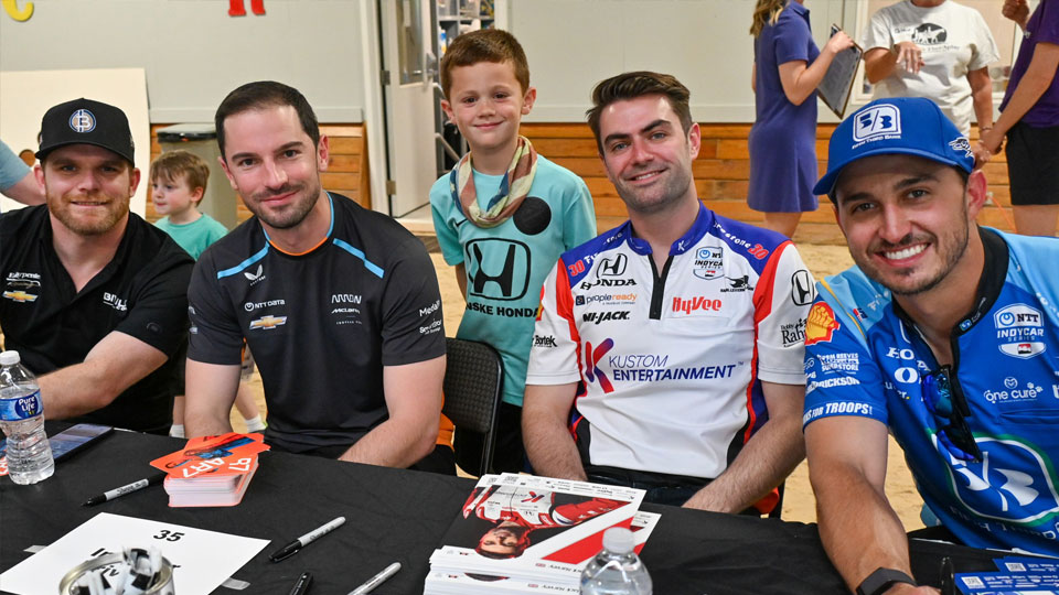 INDYCAR Drivers pose with a young fan at an autograph table