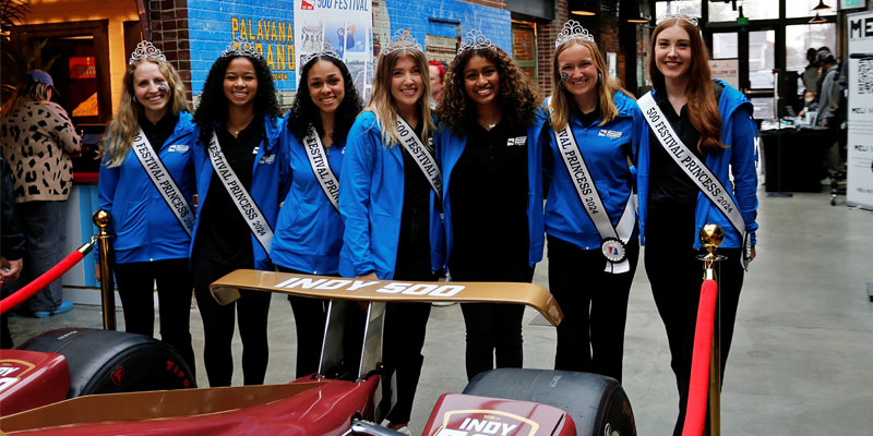 500 Festival Princess pose with the Indy 500 race car at a 2024 Fan Fest event