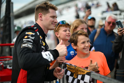 Josef Newgarden poses with a fan on pit road at Indianapolis Motor Speedway