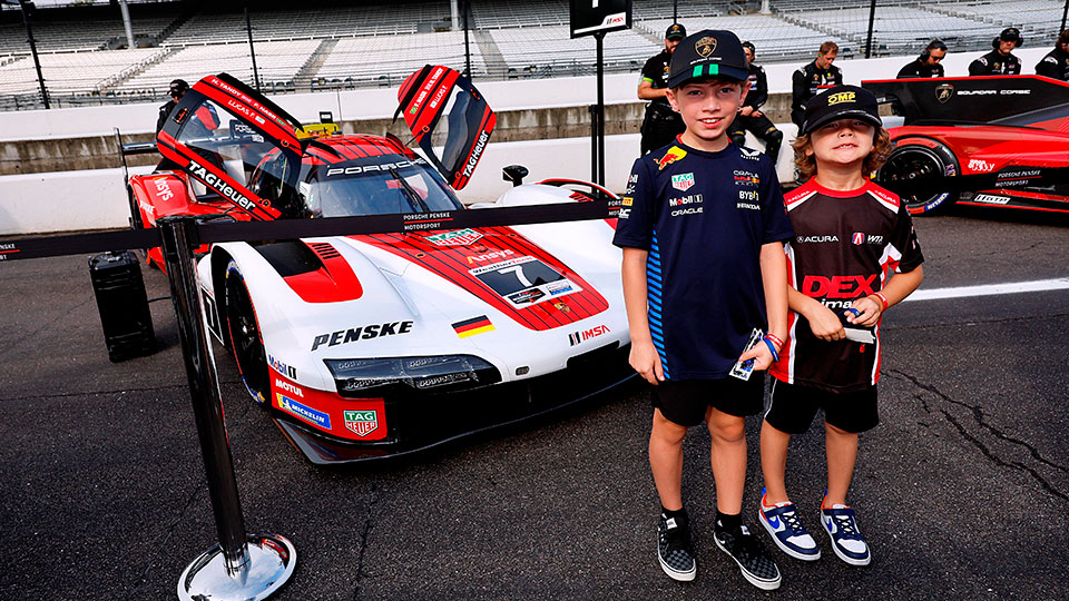 Children pose in front of a car