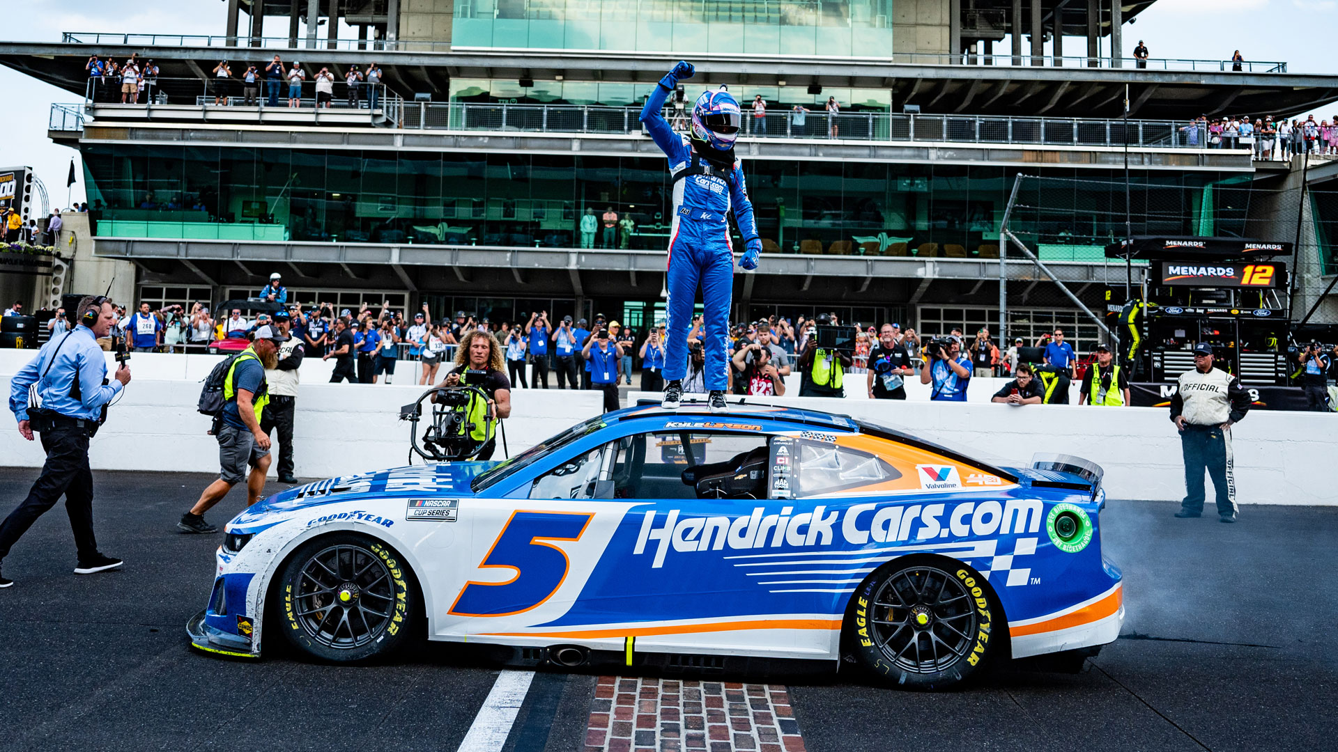 Kyle Larson celebrates his win on the Yard of Bricks while standing on top of his 5 car with the Pagoda in the background