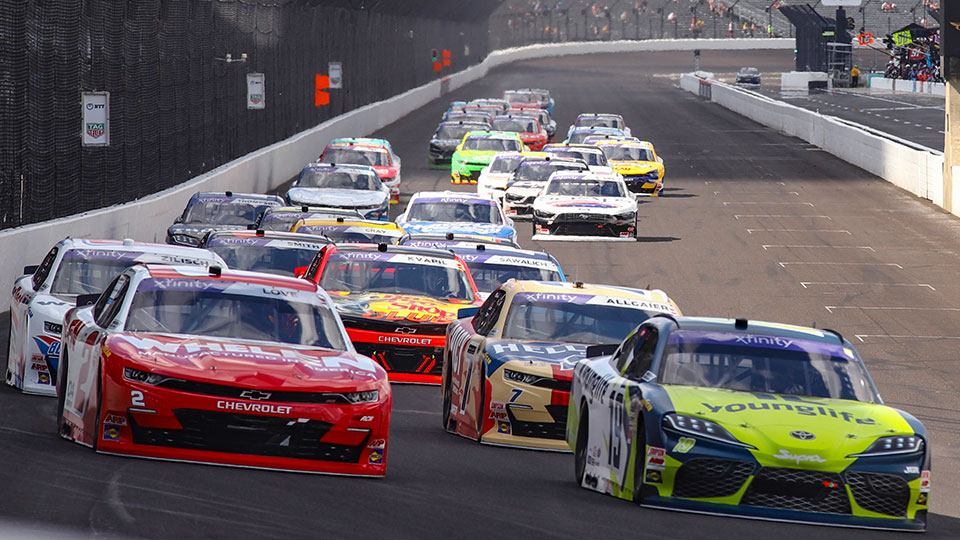 The field of Xfinity drivers drive into Turn 1 at IMS