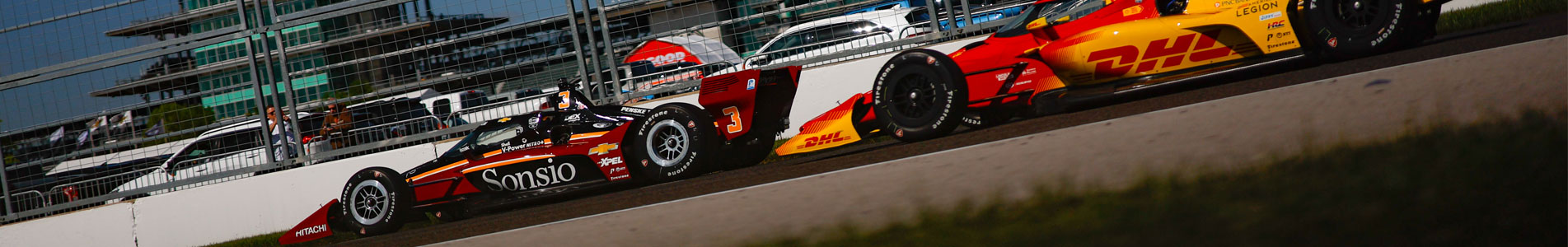 Scott McLaughlin and Alex Palou on track at Indianapolis Motor Speedway with the Pagoda in the background
