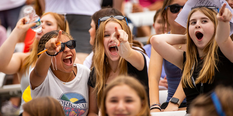 Three young fans react enthusiastically in the grandstands