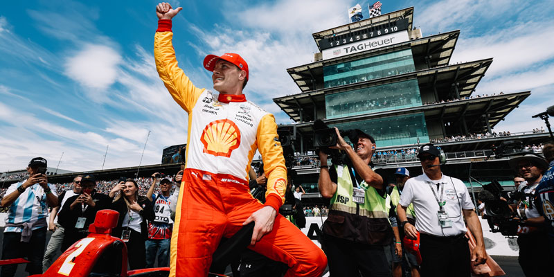 Josef Newgarden celebrates victory in the 2023 Indianapolis 500 on the front straightaway with the Pagoda in the background