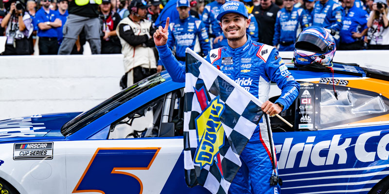 Kyle Larson celebrates victory in the Brickyard 400 Presented by PPG on the Yard of Bricks with the checkered flag in front of the 5 car