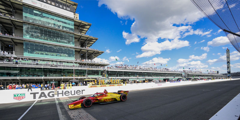 Alex Palou celebrates with fist raised in his #10 car as he crosses the Yard of Bricks at Indianapolis Motor Speedway
